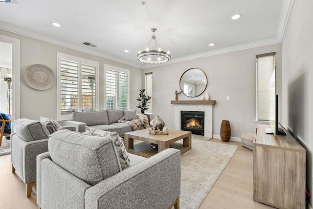 living room featuring a notable chandelier, ornamental molding, and light wood-type flooring