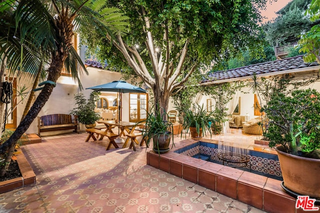 patio terrace at dusk with an outbuilding and an outdoor fire pit