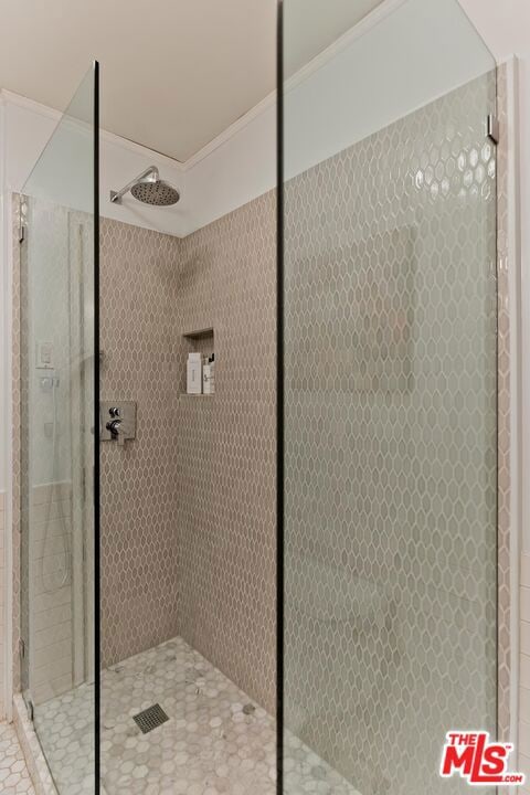 bathroom featuring ornamental molding and tiled shower