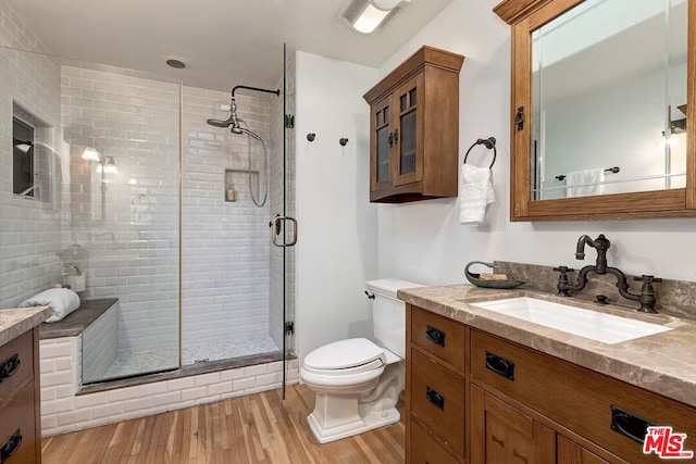 bathroom with vanity, a shower with shower door, hardwood / wood-style floors, and toilet