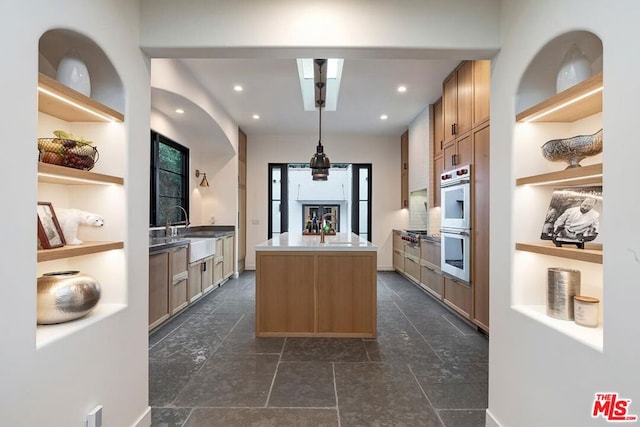 kitchen with a kitchen island, double oven, sink, white fridge, and light brown cabinets