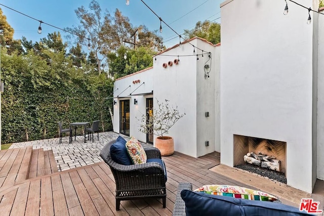 wooden terrace with a patio and an outdoor fireplace