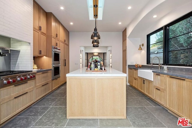 kitchen with sink, a kitchen island, pendant lighting, stainless steel appliances, and backsplash