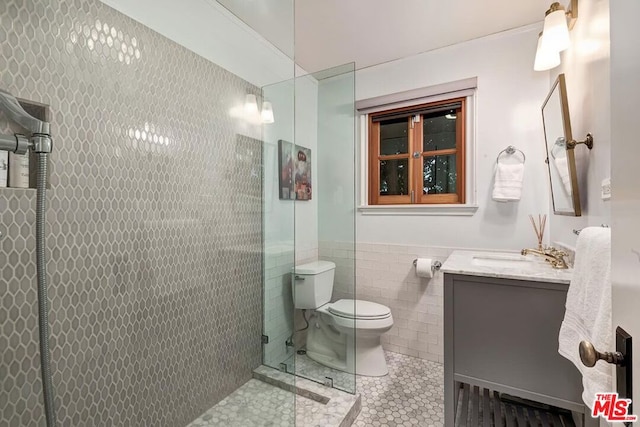 bathroom featuring tiled shower, toilet, tile walls, vanity, and tile patterned flooring