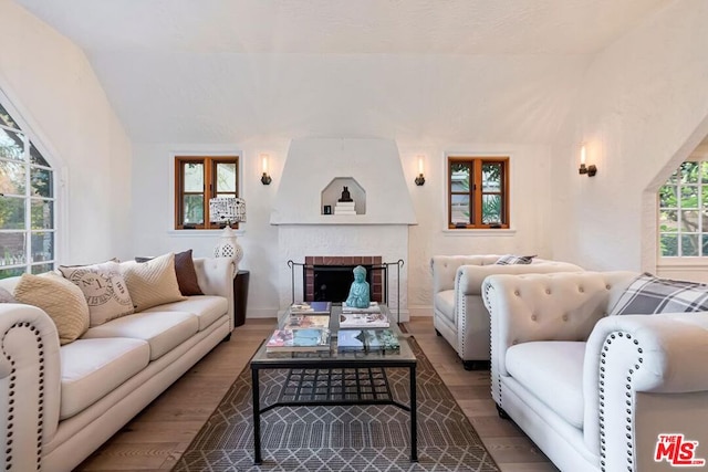 living room featuring lofted ceiling, a fireplace, and hardwood / wood-style floors