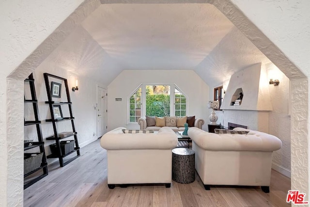 living room with vaulted ceiling, light hardwood / wood-style floors, and a textured ceiling