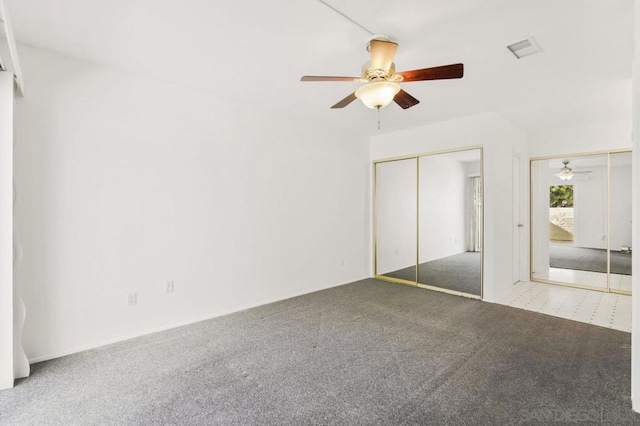 unfurnished bedroom featuring two closets, ceiling fan, and carpet