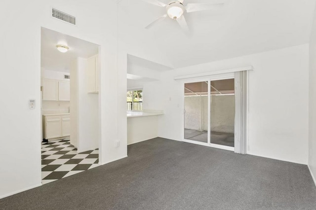 unfurnished room with dark colored carpet, vaulted ceiling, and ceiling fan