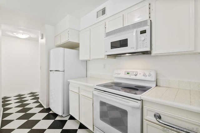 kitchen with white appliances, tile counters, and white cabinets