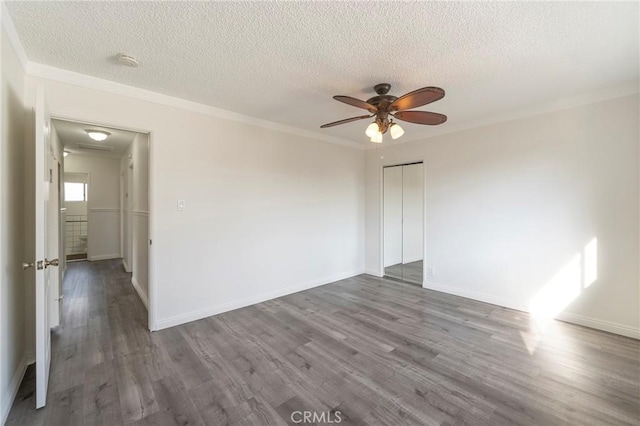 empty room with crown molding, a textured ceiling, dark hardwood / wood-style floors, and ceiling fan