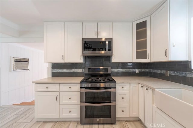 kitchen featuring backsplash, stainless steel appliances, light stone counters, and white cabinets