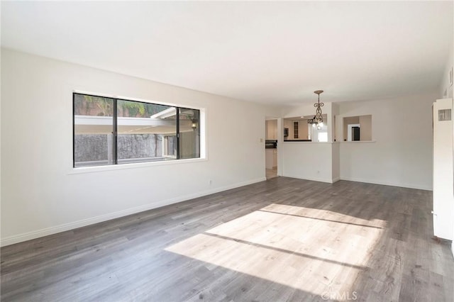 spare room with dark hardwood / wood-style floors and an inviting chandelier