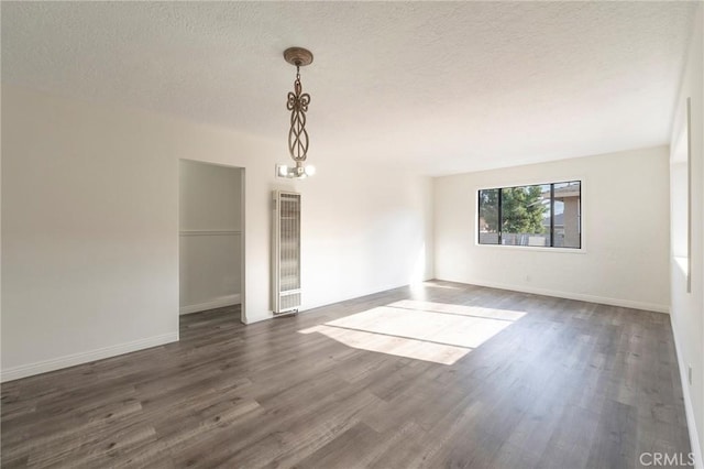 empty room featuring dark wood-type flooring, a chandelier, and a textured ceiling