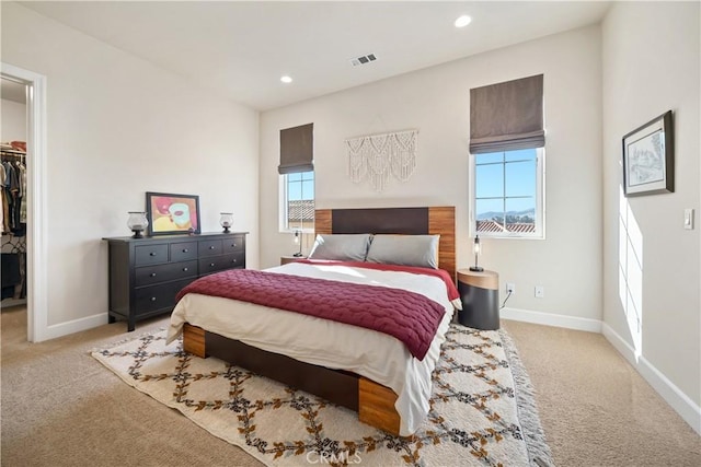 carpeted bedroom featuring multiple windows, a walk in closet, and a closet