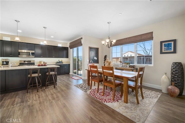 dining room with an inviting chandelier, sink, and wood-type flooring