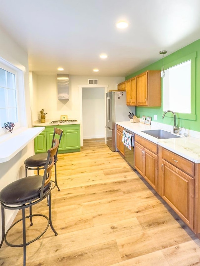 kitchen featuring stainless steel appliances, sink, pendant lighting, and light wood-type flooring