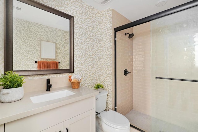 bathroom featuring vanity, toilet, and a shower with shower door