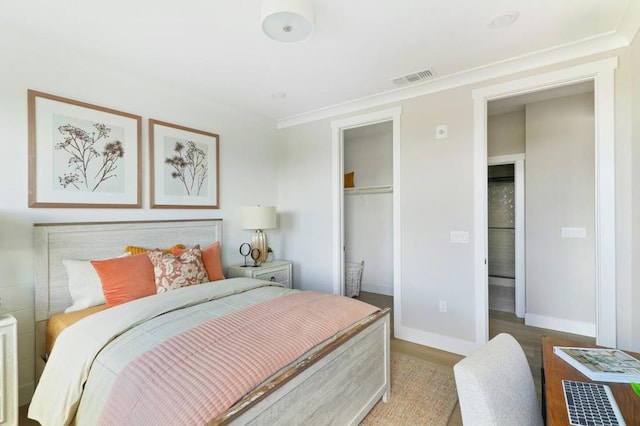 bedroom featuring hardwood / wood-style flooring, ornamental molding, and a closet