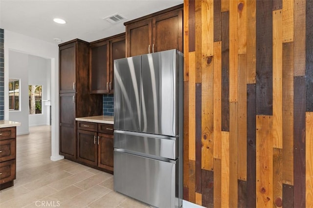 kitchen with tasteful backsplash, dark brown cabinets, stainless steel refrigerator, and light hardwood / wood-style floors