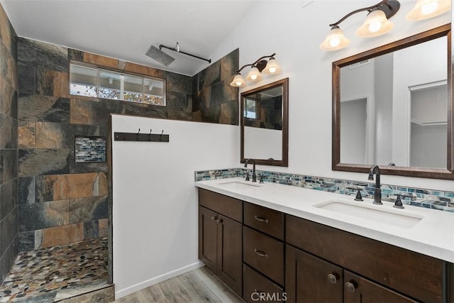 bathroom with tasteful backsplash, vanity, hardwood / wood-style flooring, and a tile shower