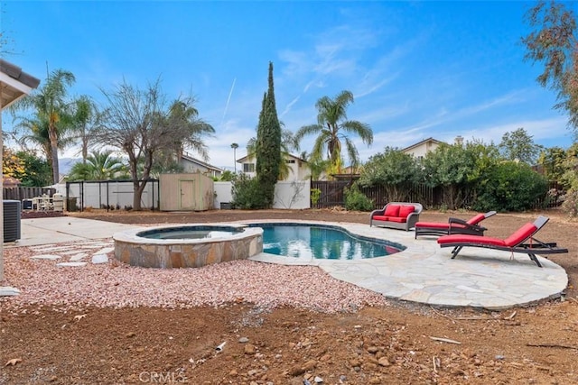 view of pool with a pool with connected hot tub, a fenced backyard, a storage unit, and a patio