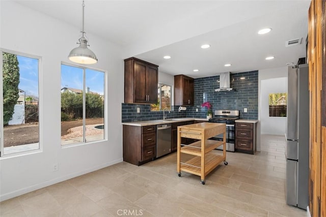 kitchen featuring dark brown cabinetry, visible vents, wall chimney exhaust hood, stainless steel appliances, and light countertops