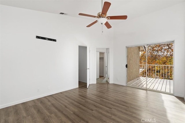 unfurnished room with visible vents, a high ceiling, ceiling fan, wood finished floors, and baseboards