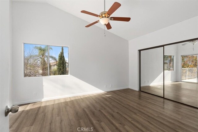 unfurnished bedroom featuring wood-type flooring, high vaulted ceiling, a closet, and ceiling fan