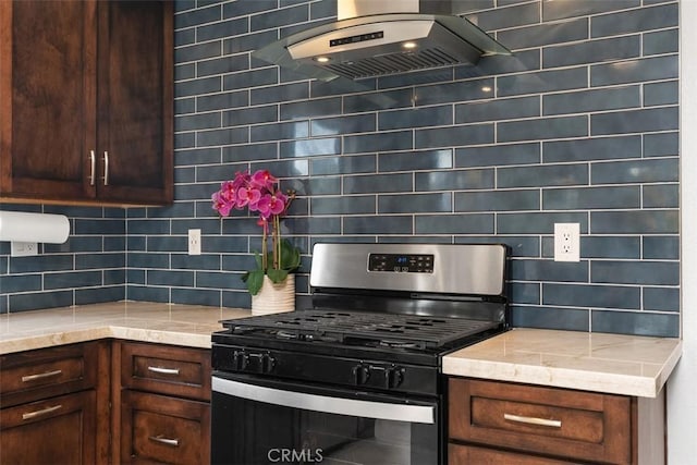 kitchen featuring stainless steel gas stove, light stone countertops, wall chimney exhaust hood, and backsplash