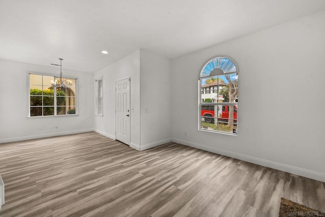 empty room with an inviting chandelier and light hardwood / wood-style floors