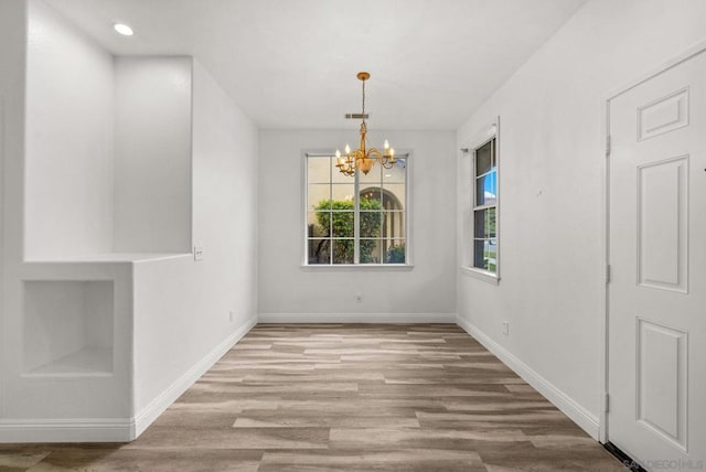 unfurnished dining area featuring a chandelier and light wood-type flooring