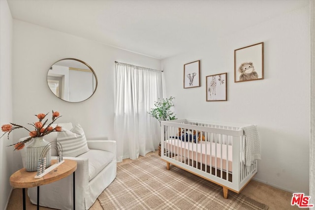 bedroom with a crib and light colored carpet