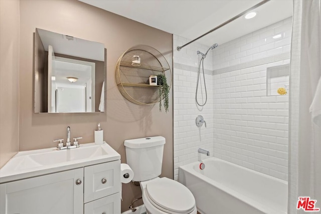 full bathroom featuring tiled shower / bath, vanity, and toilet