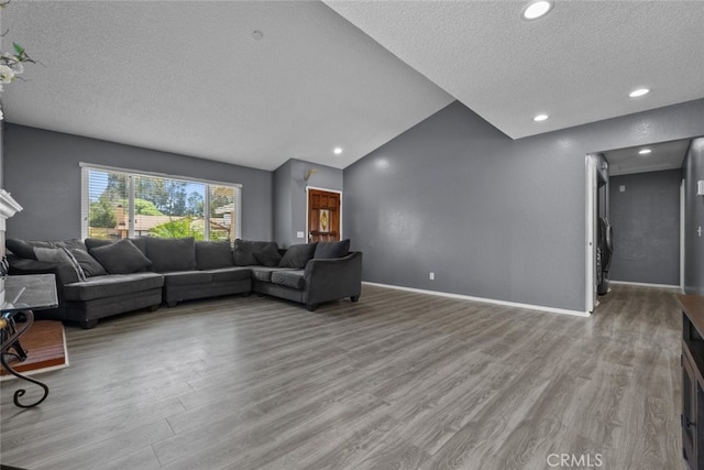 living room featuring vaulted ceiling, a textured ceiling, and light wood-type flooring