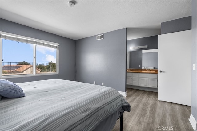 bedroom with sink, hardwood / wood-style floors, a textured ceiling, and ensuite bathroom