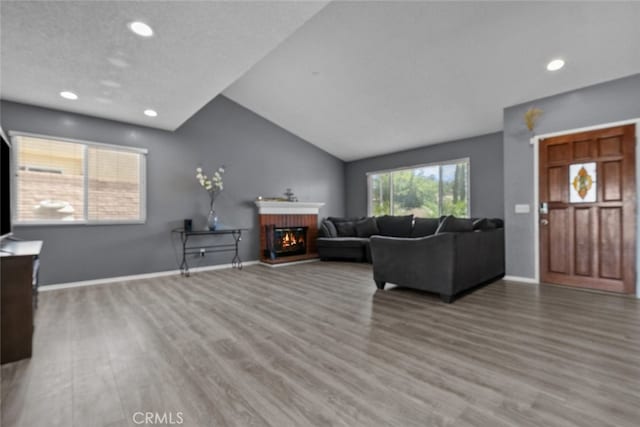 living room with lofted ceiling, hardwood / wood-style floors, a textured ceiling, and a fireplace