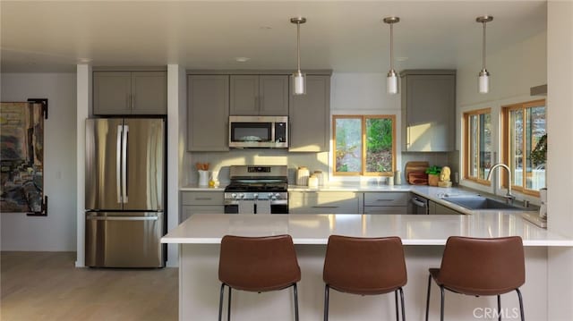 kitchen featuring sink, appliances with stainless steel finishes, a kitchen breakfast bar, decorative backsplash, and kitchen peninsula