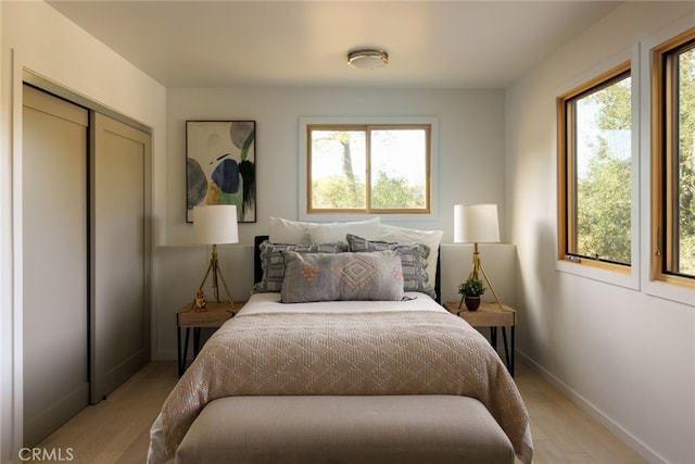 bedroom with a closet, multiple windows, and light hardwood / wood-style flooring