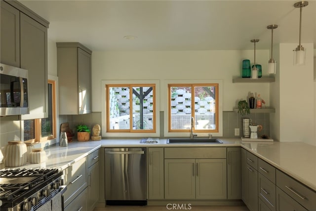 kitchen featuring sink, appliances with stainless steel finishes, backsplash, decorative light fixtures, and kitchen peninsula