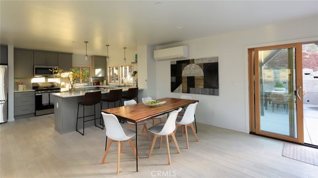 dining room with a wall mounted air conditioner, light hardwood / wood-style floors, and sink