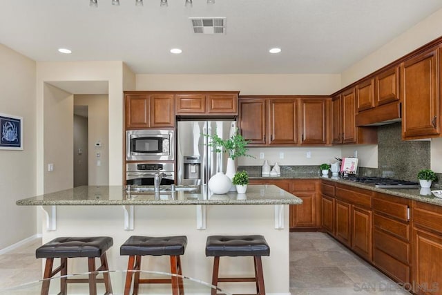 kitchen with a kitchen island with sink, stainless steel appliances, and a kitchen bar