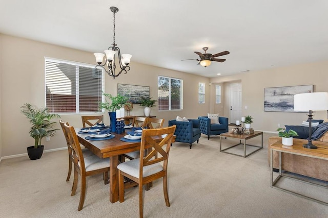 carpeted dining area with ceiling fan with notable chandelier