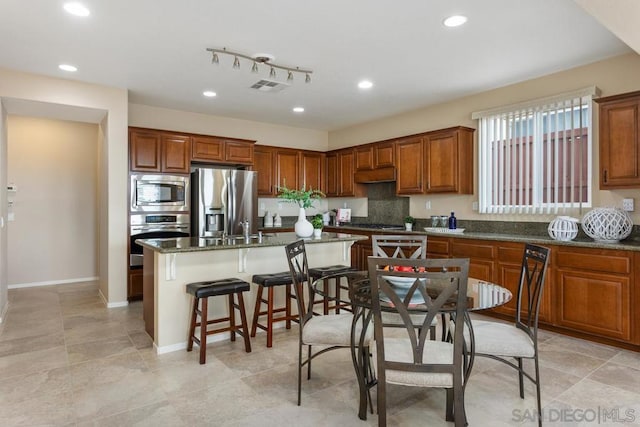 kitchen with appliances with stainless steel finishes, a center island, and dark stone counters