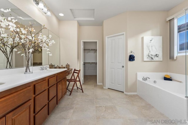 bathroom featuring tiled tub, vanity, and tile patterned flooring