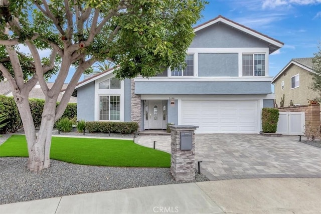 view of front facade featuring fence, a front yard, stucco siding, a garage, and driveway