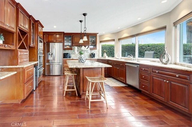 kitchen featuring pendant lighting, stainless steel appliances, a center island, a kitchen bar, and decorative backsplash