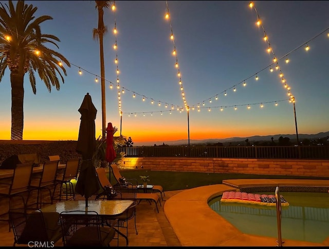 patio terrace at dusk featuring fence