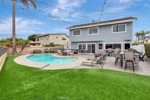 rear view of house featuring a fenced in pool, a yard, and a patio