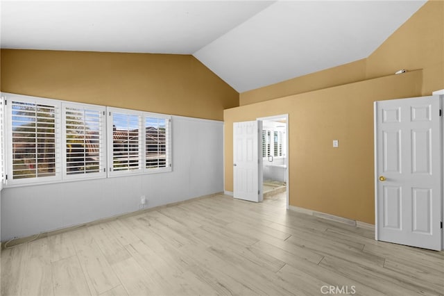 spare room featuring light hardwood / wood-style flooring and vaulted ceiling