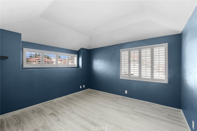 spare room featuring vaulted ceiling and light wood-type flooring